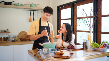 Horizontal happy couple cooking pasta together in a cozy home kitchen with warm lighting, steam rising from the pot and natural colors creating a joyful and intimate atmosphere, ideal for lifestyle