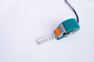 Teal and gray tape measure with metal tape extended on a white background
