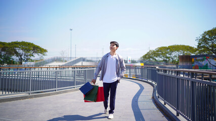 asian young man carrying shopping bags at the Rooftop walkway shopping mall