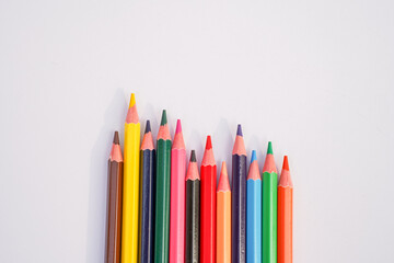 A colorful assortment of sharpened colored pencils arranged in a wave pattern on a clean white background
