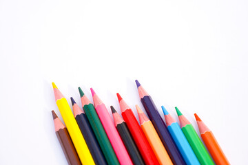 Fototapeta premium group of colorful pencils lined up diagonally on a white background with ample copy space