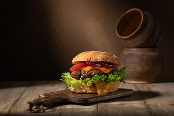 Homemade cheeseburger with greens on a rustic table