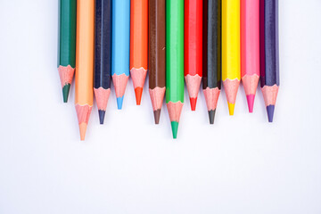 colorful pencils lined up on a white background ready for use