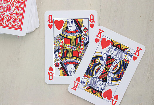 Overhead view of a King and queen of next to a stack of playing cards on a table