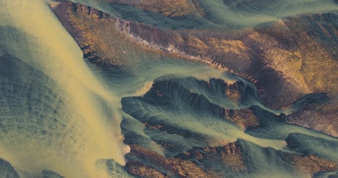 Aerial view of winding river streams weaving through the rugged terrain, showcasing a mesmerizing blend of colors and textures, Hvolsvollur, Rangarping eystra, Iceland.