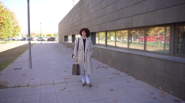 A Stylish Woman is Walking Gracefully in an Urban Environment Surrounded by Modern Architecture