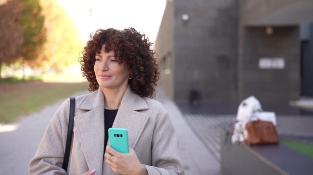 A Smiling Young Woman with Beautiful Curly Hair Joyfully Posing Outdoors in Nature