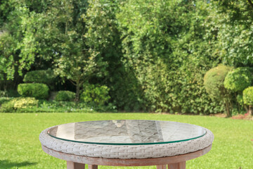 Obraz premium Empty round glass table top with abstract blur green park garden background