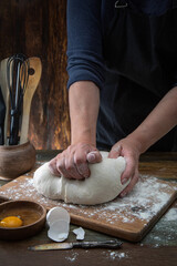 A woman kneads dough on a wooden table