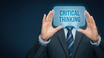 Fototapeta premium Businessman in a suit holding a hologram between hands with the words critical thinking glowing inside