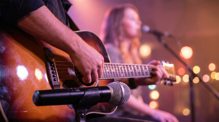 Fototapeta na wymiar Musician playing guitar on stage with a microphone during a live music concert performance