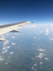 Fototapeta premium Aerial view from Sukhoi Superjet 100 window flying over Russia, airplane wing above clouds, international flight passenger perspective. June 2013.