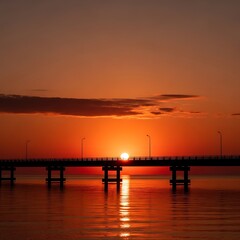 Obraz premium Sunset over calm sea with bridge.