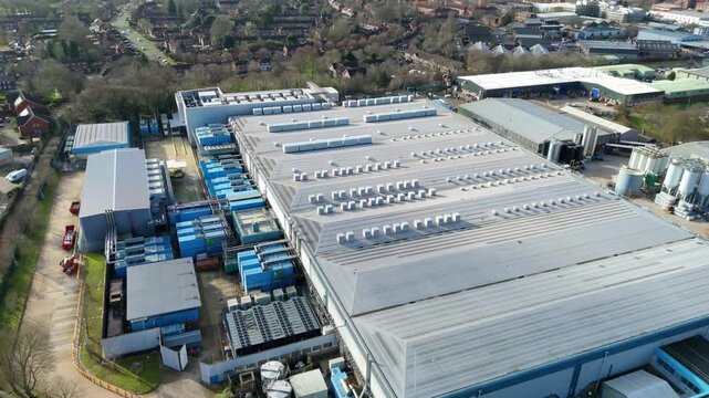 Aerial view of Colt Data Centre Services, a sprawling industrial complex with metallic roofs and blue containers, Welwyn Garden City, United Kingdom.