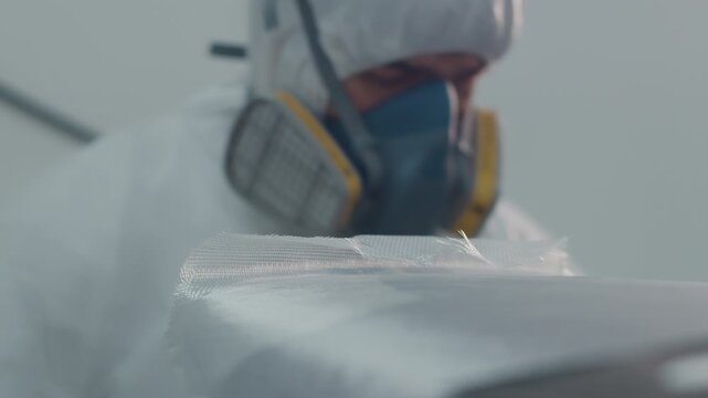 Surf board factory. Adult male shaper creates the surfing board on the factory and does glassing