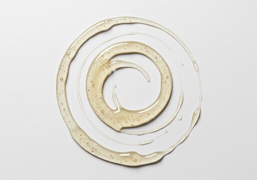 A viscous, clear adhesive substance is arranged in a perfect circular form upon a smooth white background, emphasizing bonding properties ,adhesive ,material ,fluid