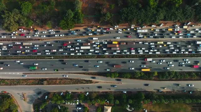 Aerial view of heavy traffic on NH 8, a major highway, presents a tapestry of vehicles amidst the green landscape, Gurugram, Haryana, India.