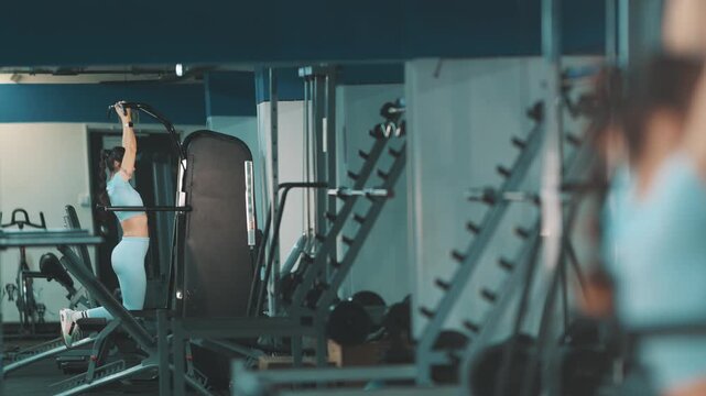 Determined athlete training body on assisted pull-up machine