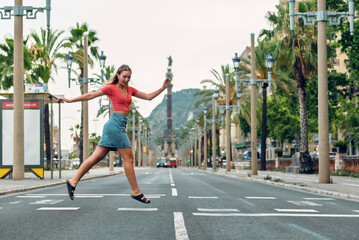 Obraz premium Beautiful woman jumping across the crosswalk while sightseeing around the city in the summer