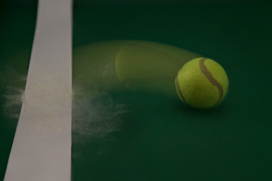 Close-up of a Tennis ball bouncing on the baseline of a tennis court with chalk dust cloud