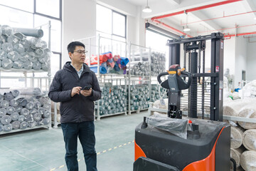 Worker operating intelligent forklift in warehouse for logistics and material handling tasks