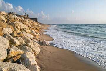High tide beach with walkers and rock erosion protection in Lacanau
