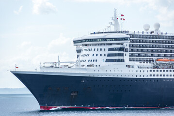 Modern cruise liner traveling across calm ocean waters under a clear blue sky, passenger vessel at sea.