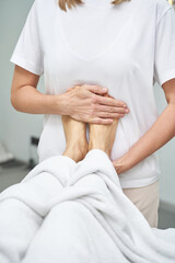 Naklejka premium Female caucasian adult performing relaxing foot massage therapy in a spa setting for stress relief and relaxation.
