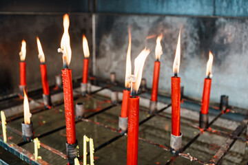 Row of lit red candles in metal holders symbolizing faith, devotion, and traditional worship ritual
