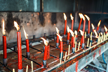 Row of lit red candles in metal holders symbolizing faith, devotion, and traditional worship ritual