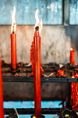 Row of lit red candles in metal holders symbolizing faith, devotion, and traditional worship ritual
