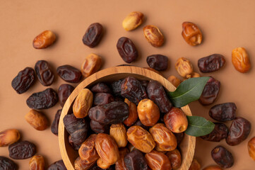 Fototapeta premium Dried dates in wooden bowl on brown background. Delicious sweet dried fruits flat lay top view. Date palm fruits, organic dates. Healthy vegan dessert