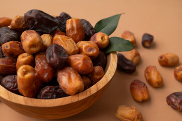 Obraz premium Dried dates in wooden bowl on brown background. Delicious sweet dried fruits flat lay top view. Date palm fruits, organic dates. Healthy vegan dessert