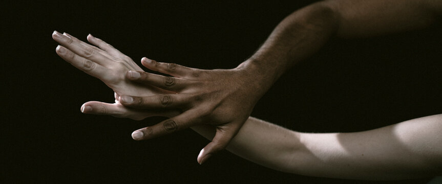 This image captures two hands locked in a firm grasp, representing themes of unity and deep emotional connection, surrounded by an aura of artistry and contrasting shadow.