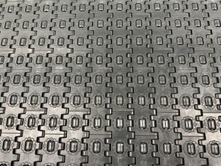 Industrial Conveyor System: Close-up of mechanical conveyor belt rollers and track connectors in a factory automation setting with geometric symmetry.