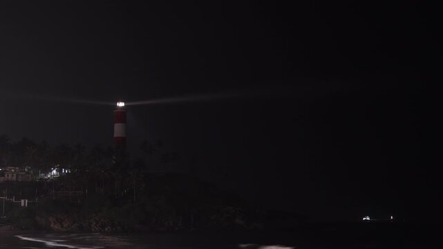 Vizhinjam Light House as seen from Kovalam beach at night long shot with sea.