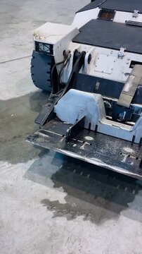 Ice Resurfacer Cleaning Indoor Rink Surface, Machine Blade Smoothing Ice With Water Sheen, Motor Hum Implied, Arena Maintenance Routine And Industrial Taken on mobile device.