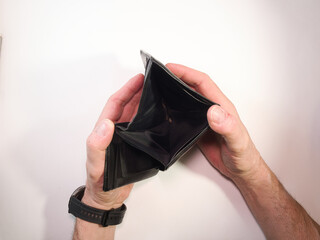 Empty Wallet in Hands - Top view of a man's hands opening an empty black wallet on a white background, symbolizing poverty, financial hardship, and economic crisis.