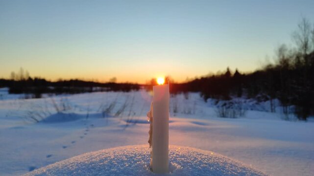 A candle burns at sunset