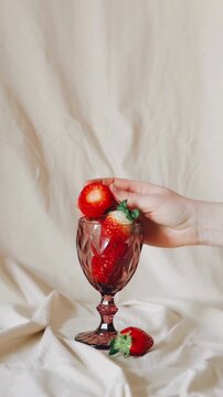 Hand Placing Fresh Organic Strawberries into a Vintage Crystal Goblet