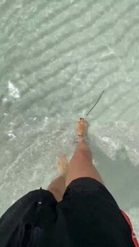 Relaxing Summer Vacation Concept - Walking Barefoot in Transparent Sea Water on White Sand