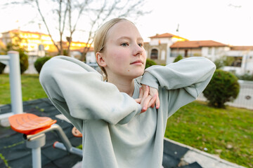 Teenage girl resting after outdoor workout in city park, calm moment, recovery, healthy lifestyle, balance between activity and rest
