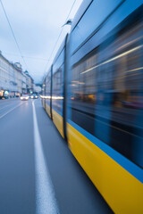 Fototapeta premium Motion blur of a yellow and blue tram moving fast through a European city street