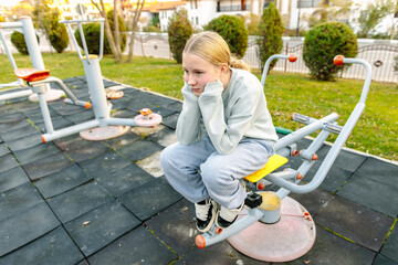 Teenage girl resting on outdoor fitness equipment after workout, emotional fatigue, pause, recovery, mental health, resilience and self awareness concept
