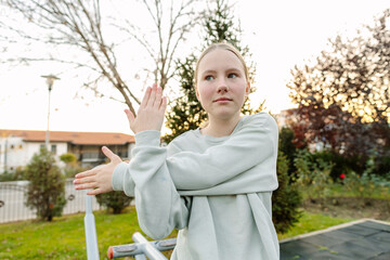 Teenage girl practicing mindful stretching in a city park, body awareness, balance, self regulation, calm focus and emotional wellbeing concept
