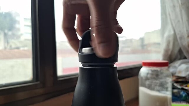 Close-up of Hand Opening a Reusable Water Bottle Cap