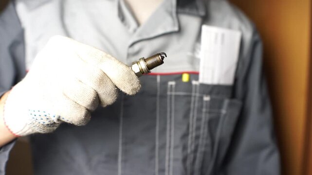 A mechanic shows old spark plugs. Defective spark plugs covered in motor oil and soot. Replacing spark plugs.