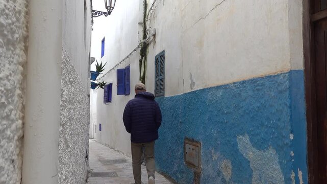 Rabat, Morocco A tourist man walks in the picturesque back alleys of the Kasbah Oudaya, The Kasbah of the Udayas, also spelled Kasbah of the Oudaias or of the Oudayas.