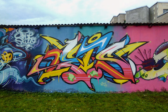 OSTROVETS, GRODNO REGION, BELARUS - MARCH 03 2011: A vibrant piece of urban graffiti art covers a long concrete wall under a cloudy sky