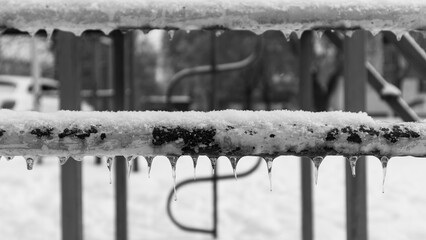 Small icicles on an old rusty iron pipe in black and white